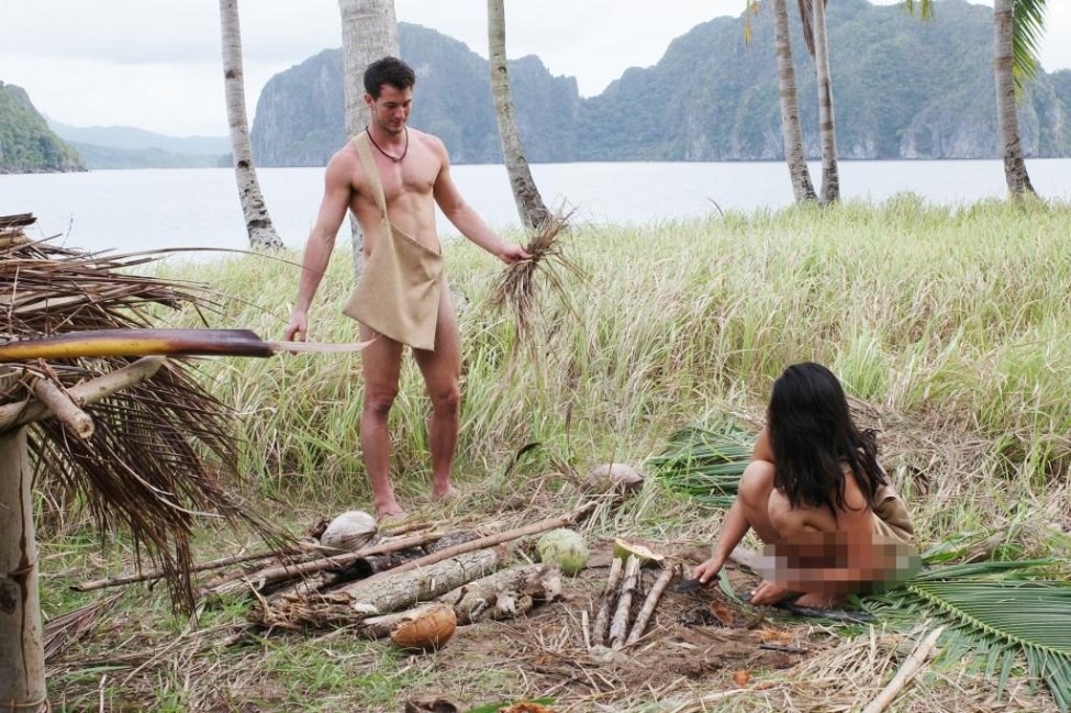 Two contestants who are naked work together to build something in the wild