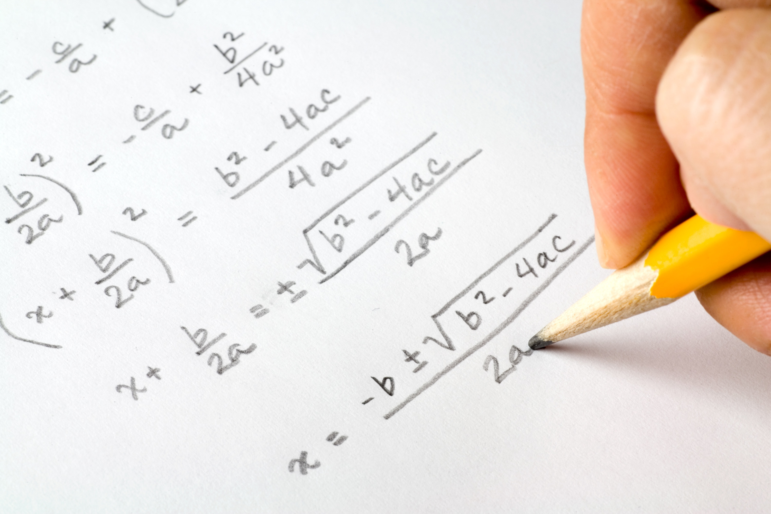 a hand writing out the quadratic formula