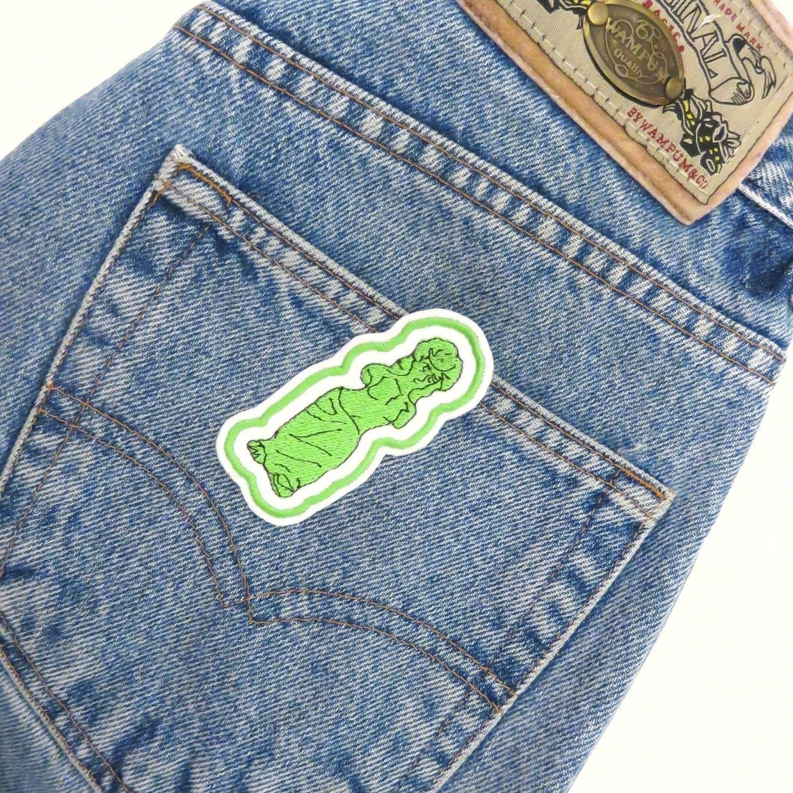 patch shaped like a gummy venus de milo statue sewn onto the back of jeans