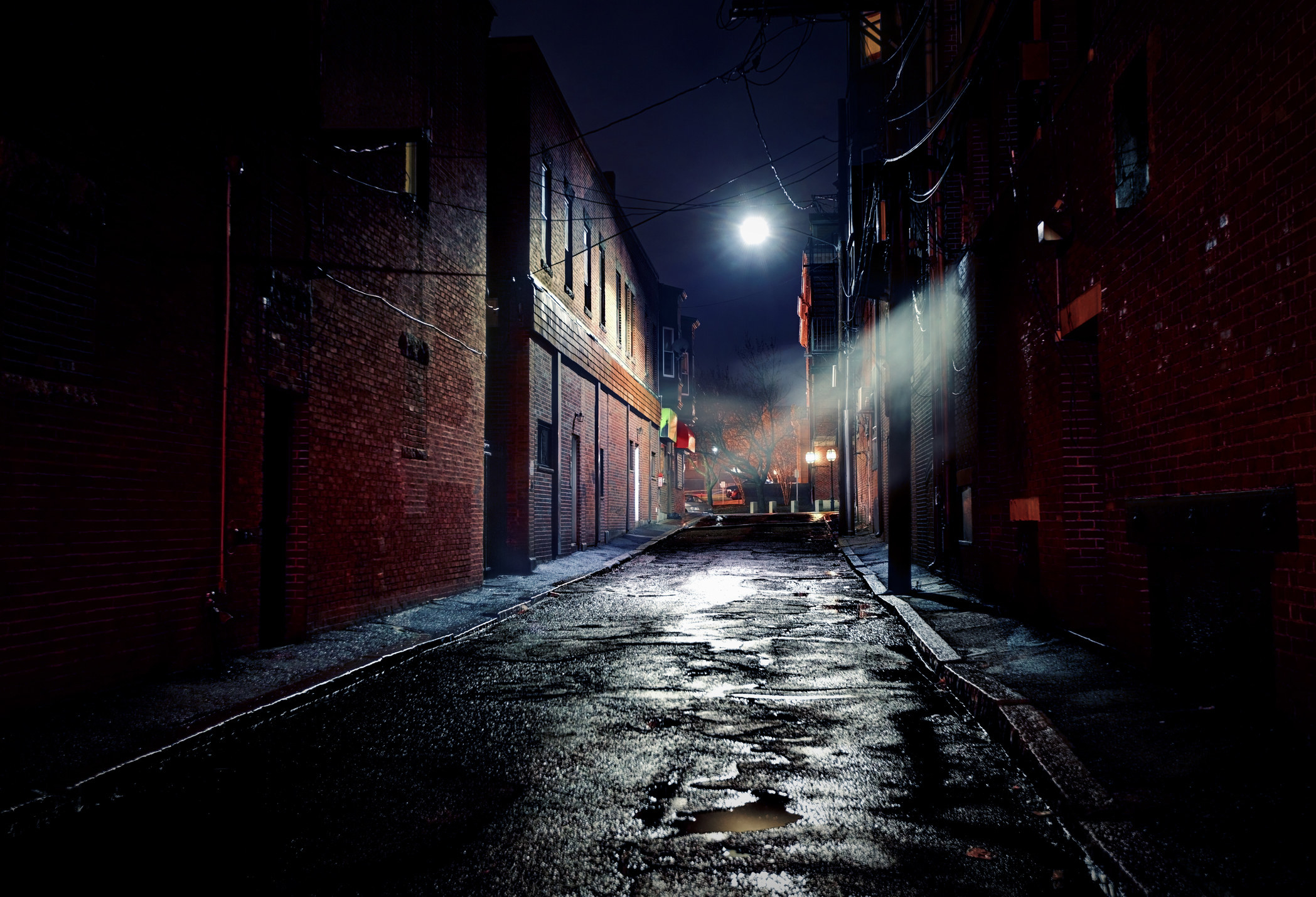Long, dark gritty alley between two old, derelict buildings at night