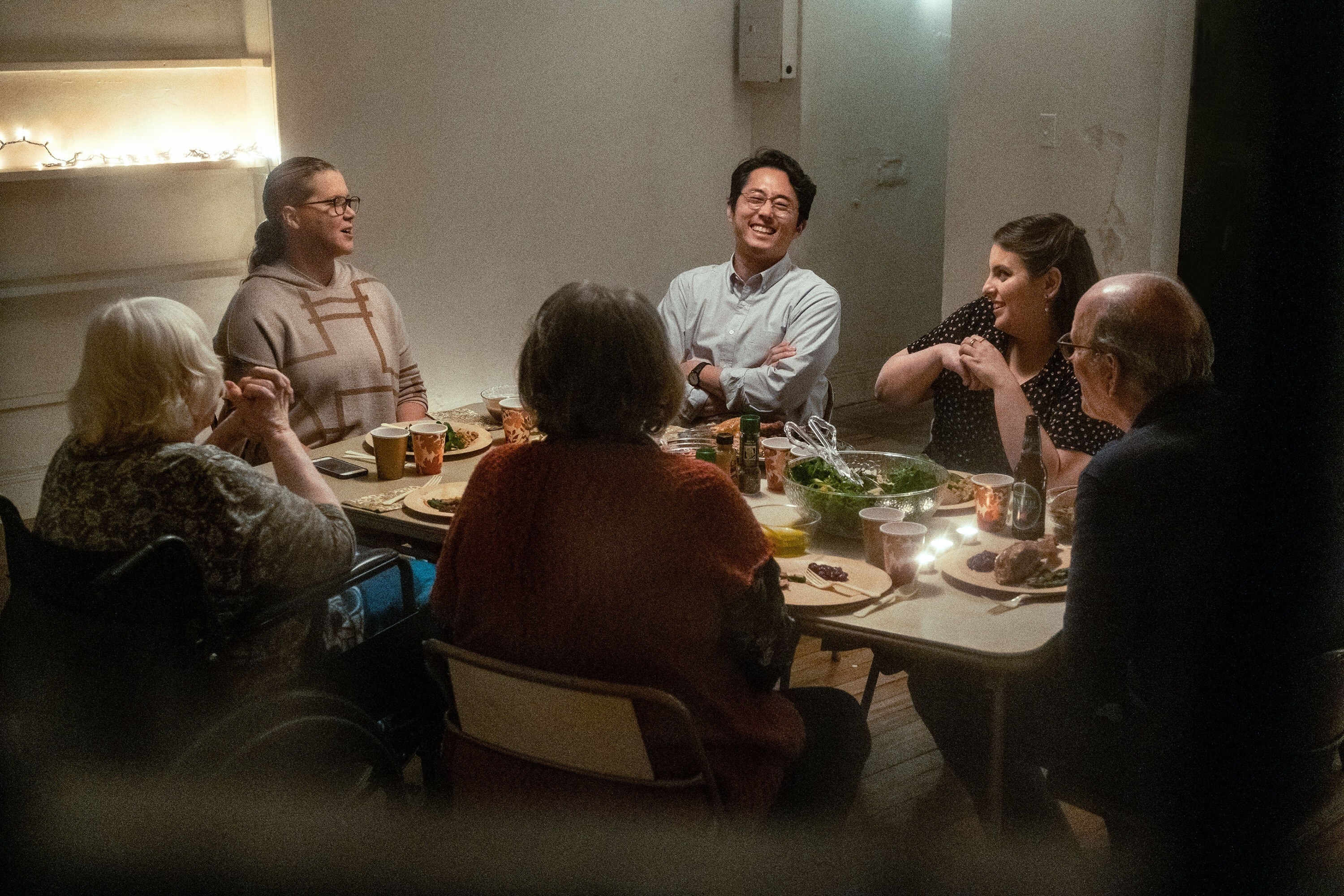 A white family, two adult sisters, one with an Asian boyfriend, their father, mother, and grandmother sit around a Thanksgiving table. Some laugh, some smile