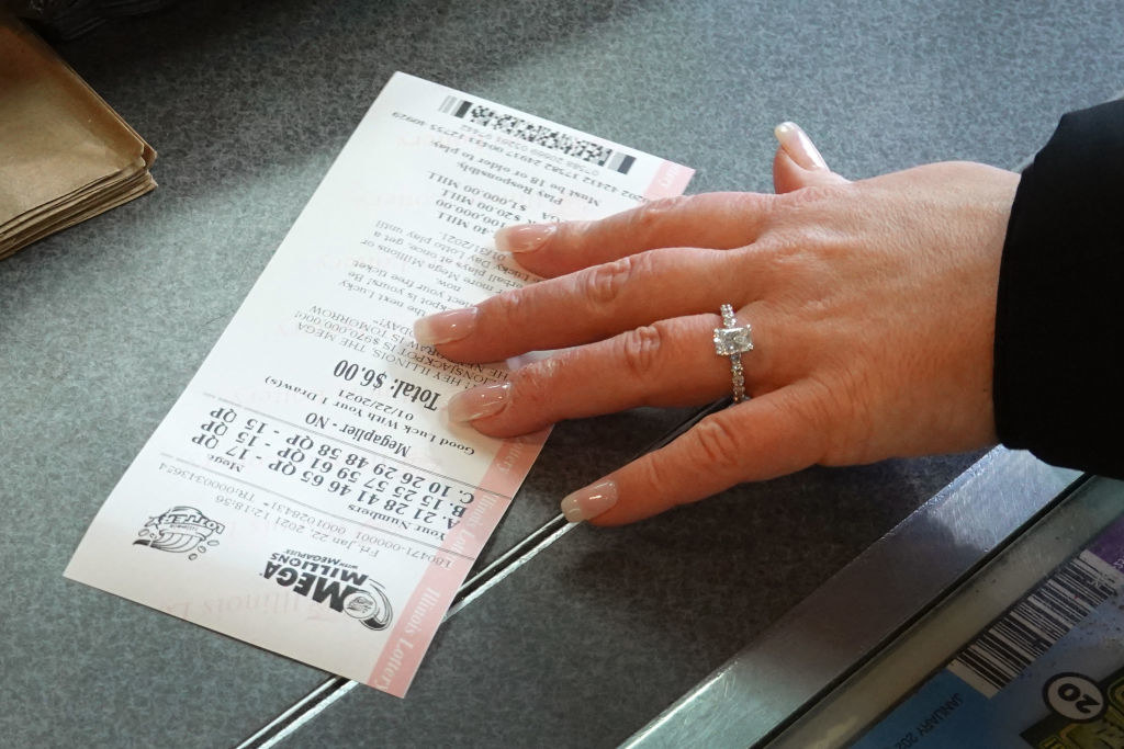 A woman passing a mega millions ticket to a clerk