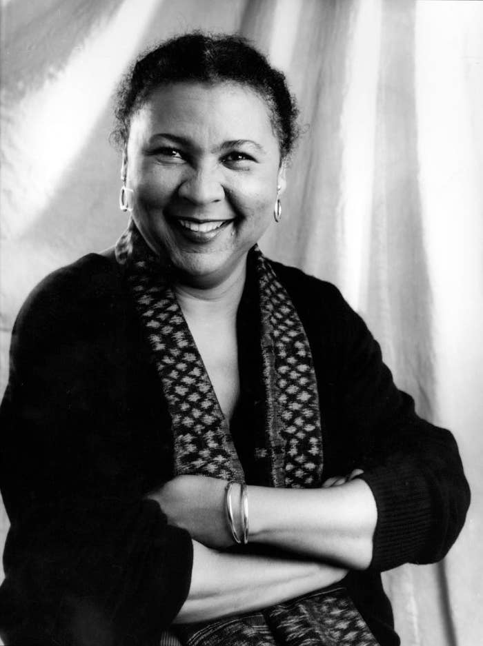 portrait of American author and feminist bell hooks (born Gloria Jean Watkins) as she smiles, her arms folded, New York, 1980s.