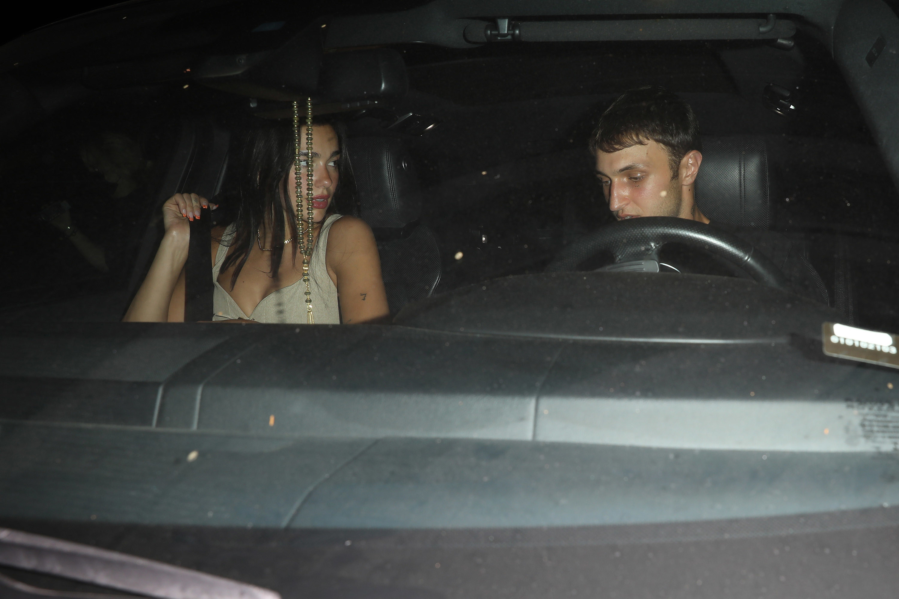 Dua and Anwar look at each other while in the front seats of a car