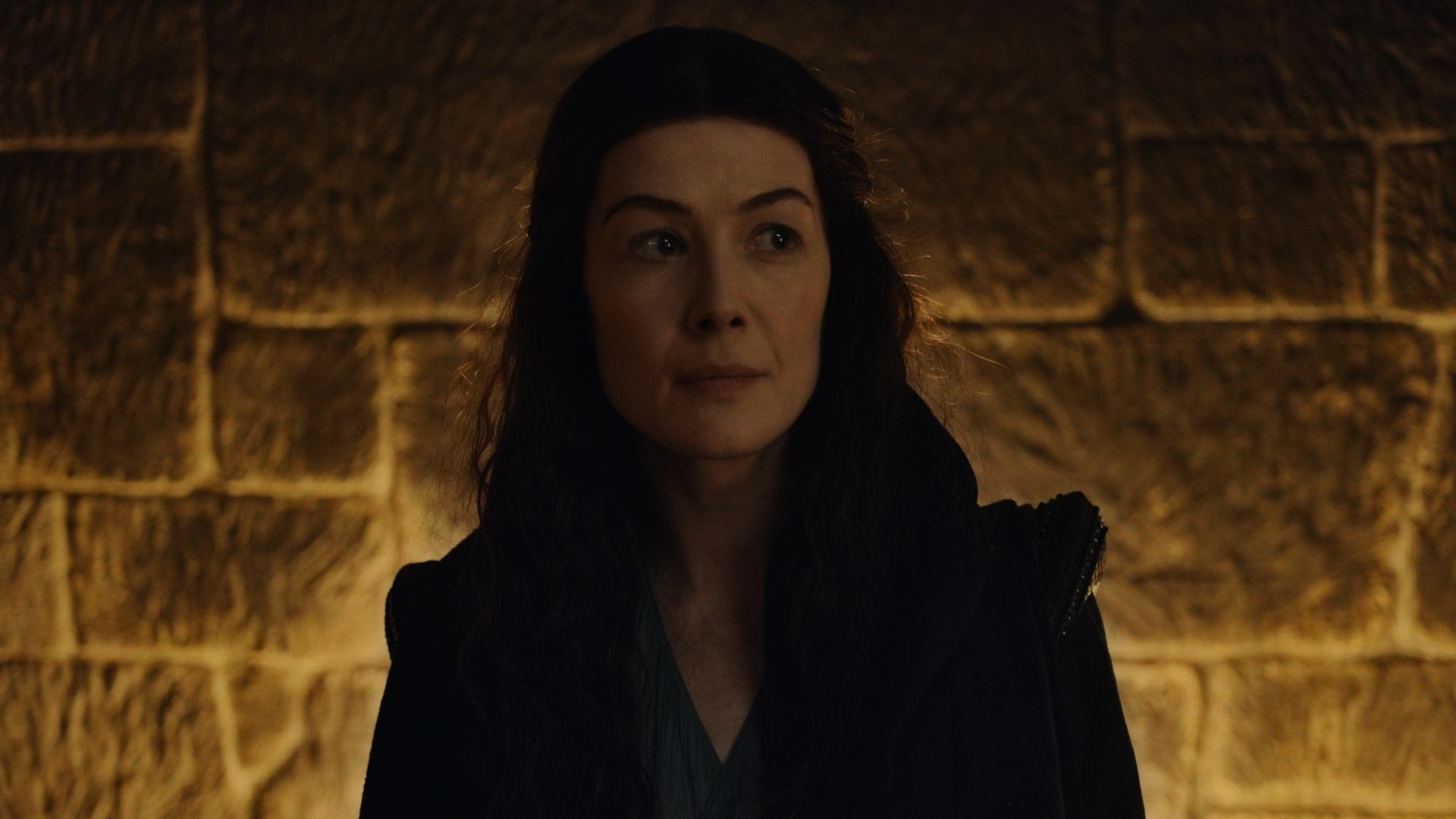 A shot of Moiraine Sedai’s (Rosamund Pike) face in the Winespring Inn, lit from behind by a large hearth