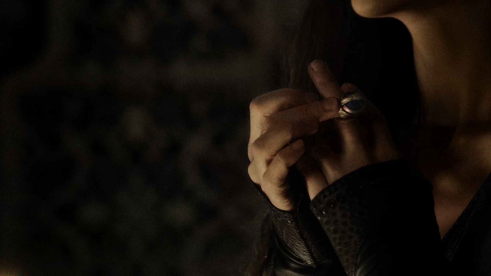 A close-up on Moiraine, focusing on the middle finger of her left hand as she dons her Aes Sedai ring, an oversized golden ring with a large blue gemstone with a serpent eating its own tail surrounding it