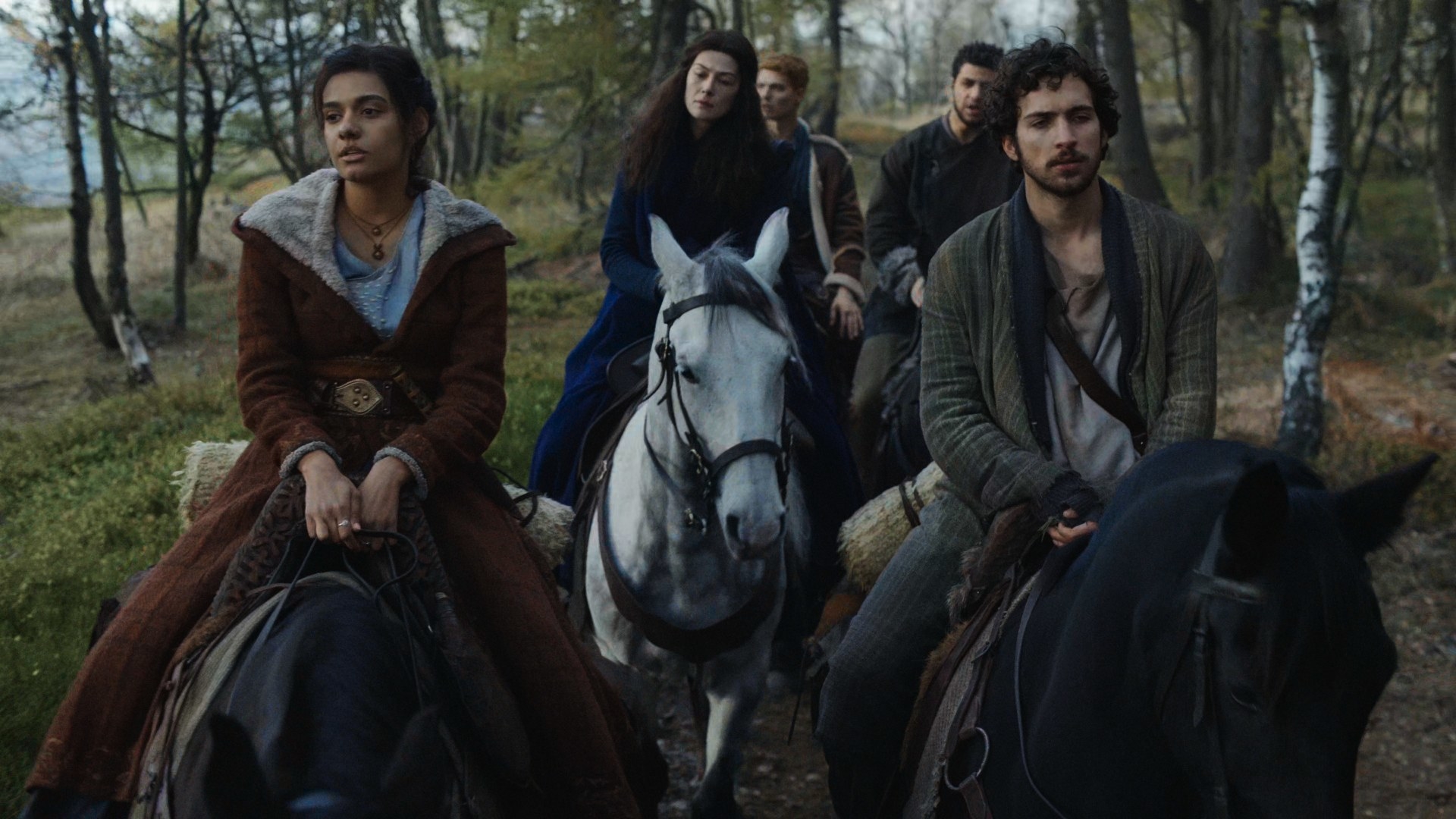 Rand, Perrin, Mat, and Egwene are all riding their horses in the wilderness, surrounding Moiraine on her white horse, Aldieb