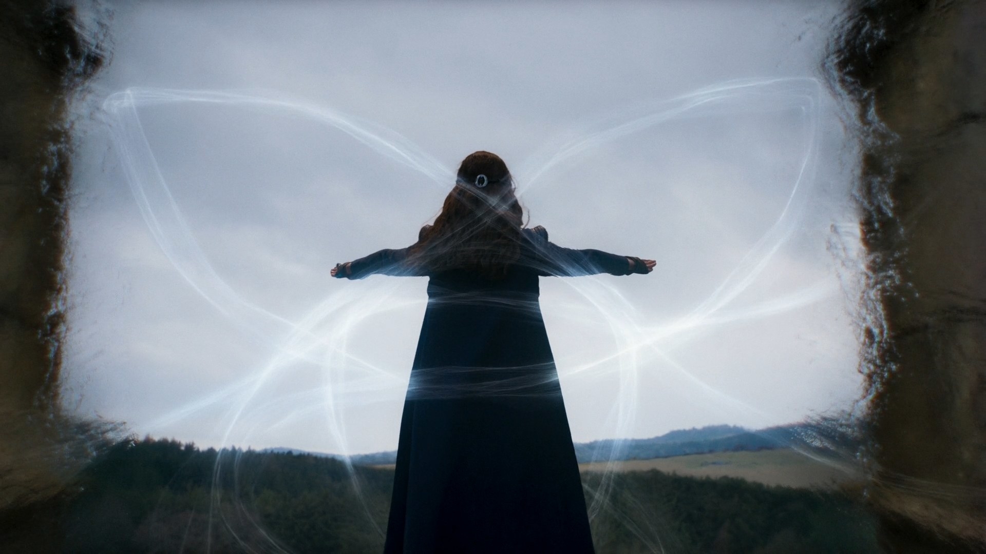 A shot of Moiraine’s back, weaving flows of the one power into the Waygate. The flows appear to be looping into a triangular shape, reminiscent of the trefoil Avendesora leaf.