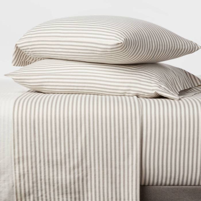 A set of white and grey striped sheets draped on a bed