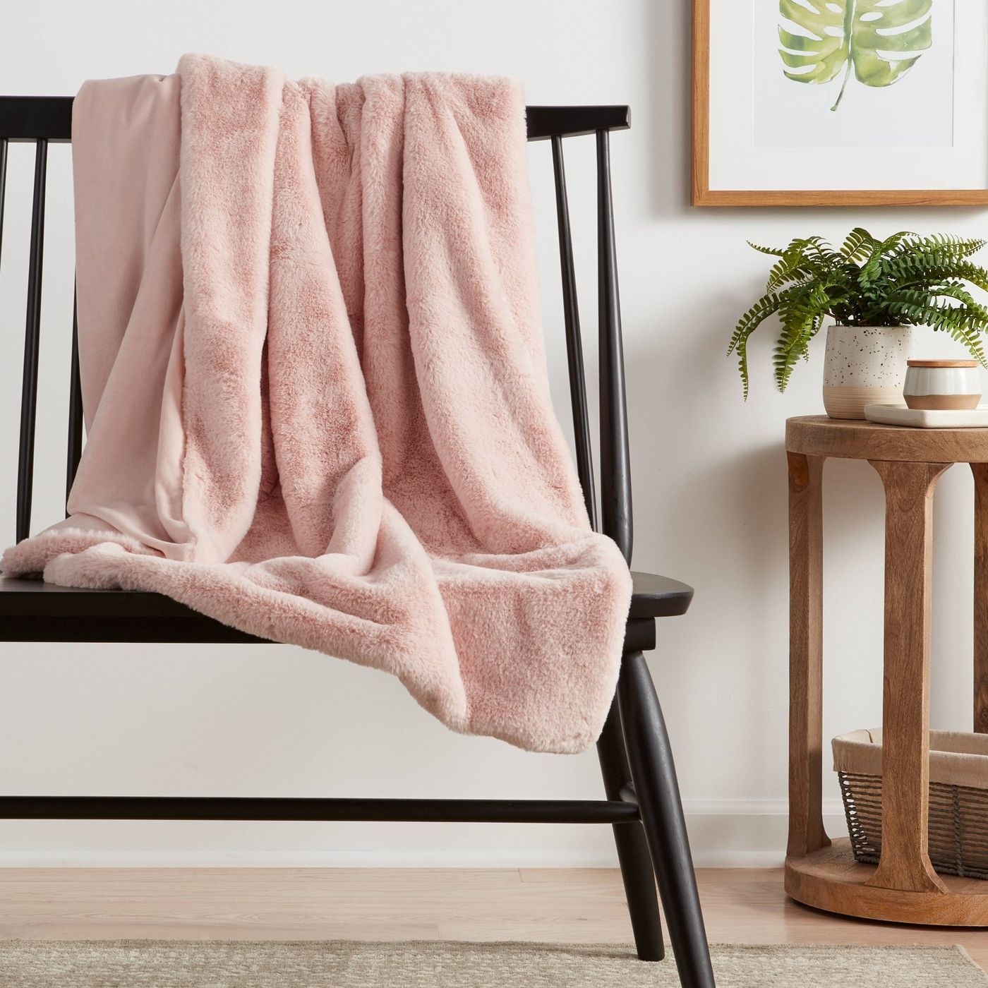 A pink fuzzy blanket draped over a black wooden chair
