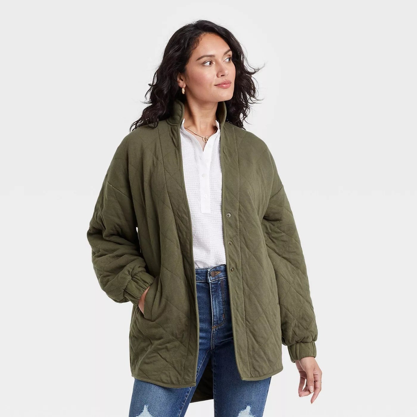 Model wearing green jacket with elastic sleeves, goes past the hip