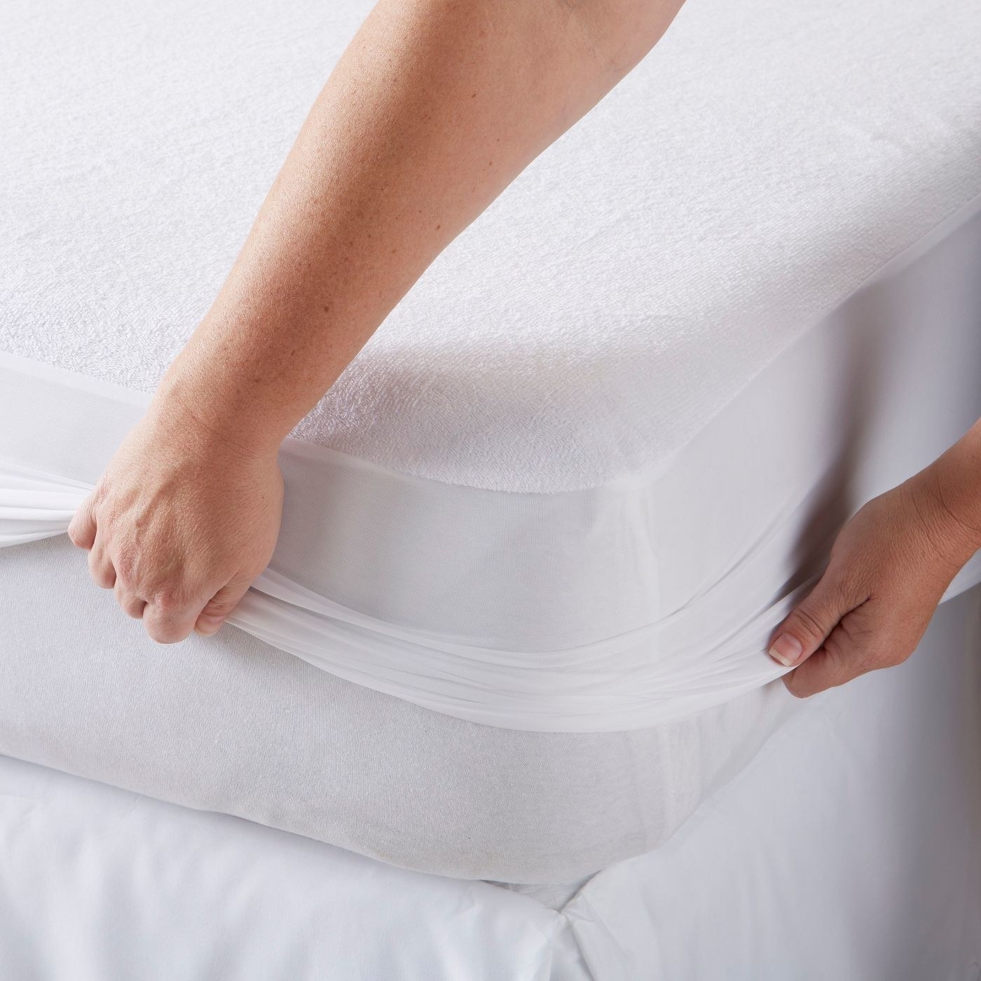 A woman zips a waterproof mattress protector onto a mattress.