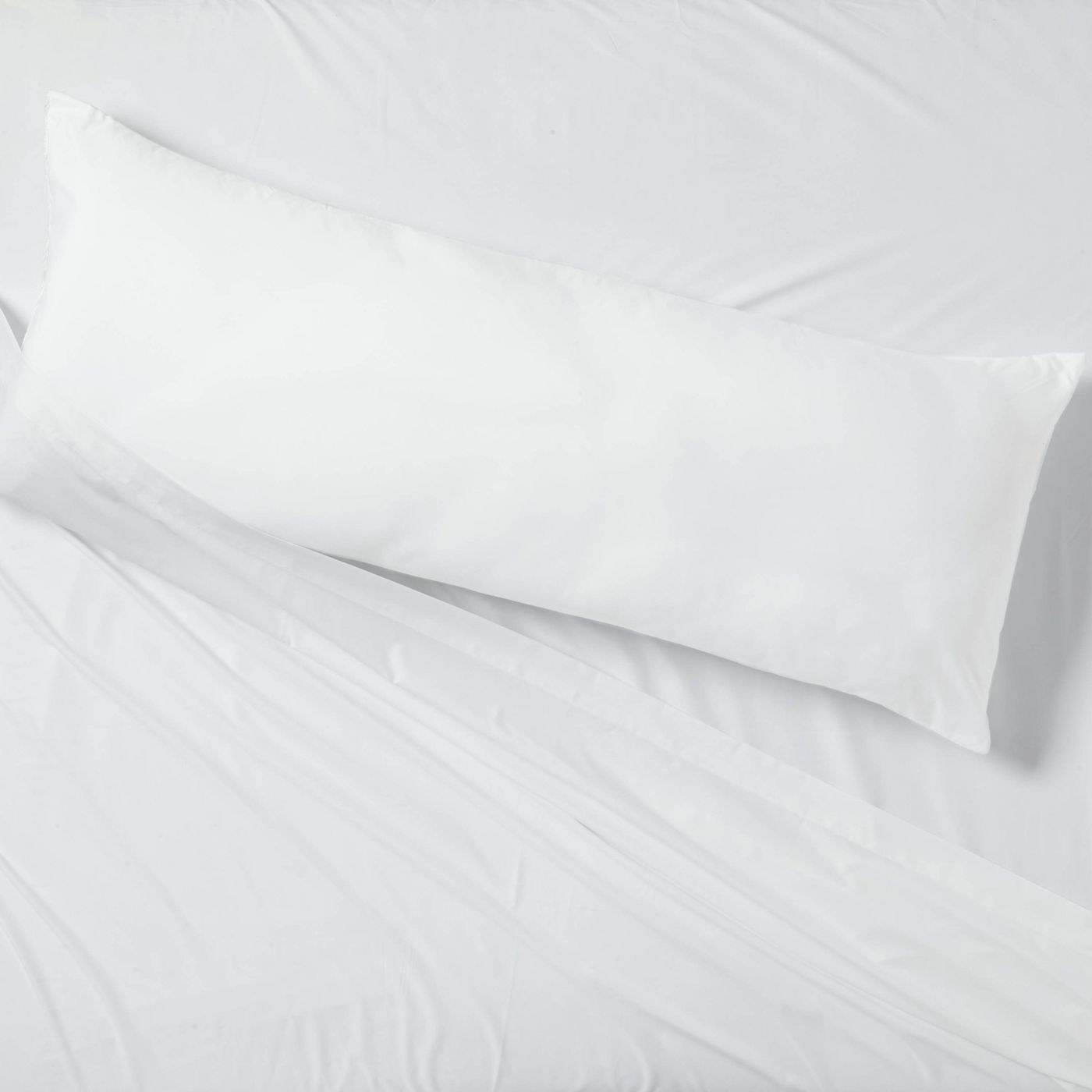 A long body pillow on a white bed