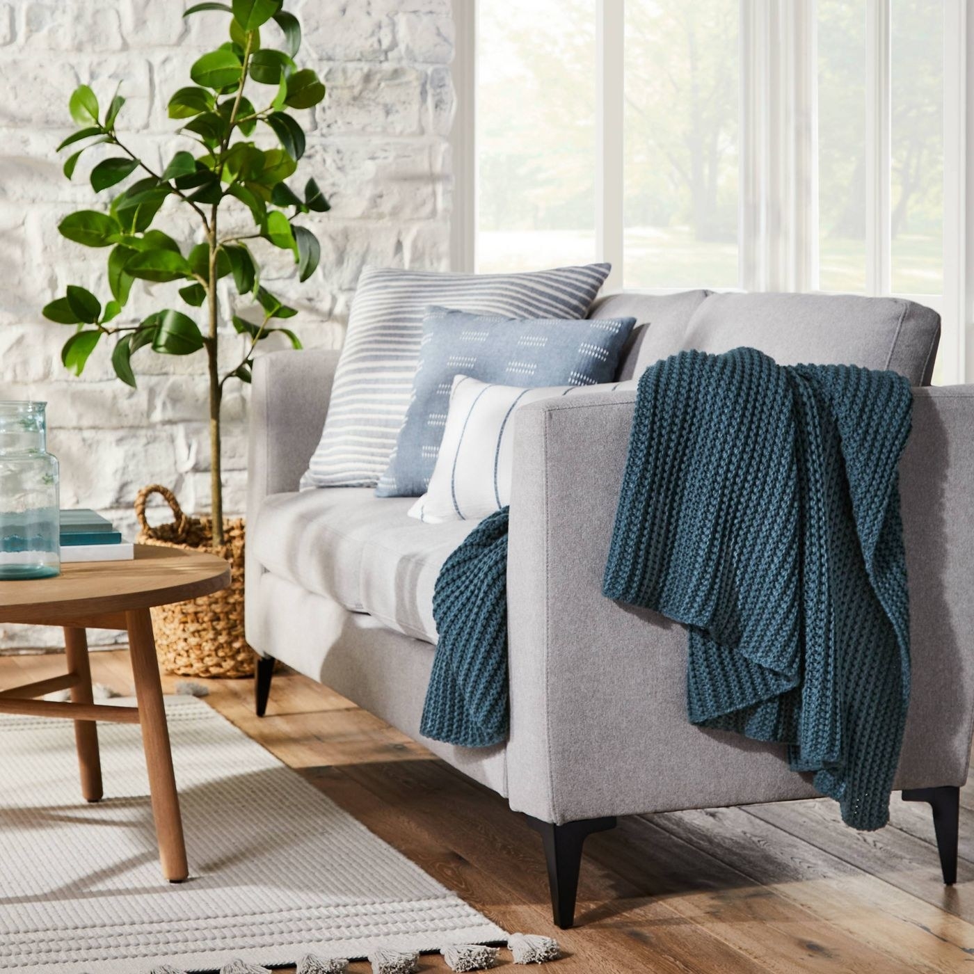 A grey sofa with a blue knit blanket