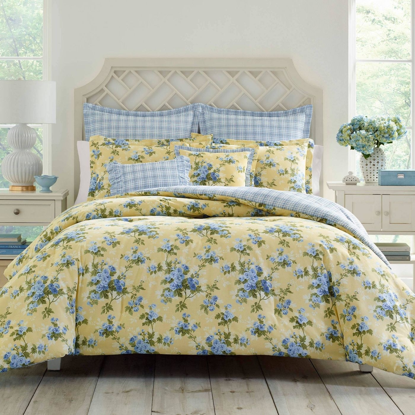 A bright yellow comforter with blue flowers on a bed.