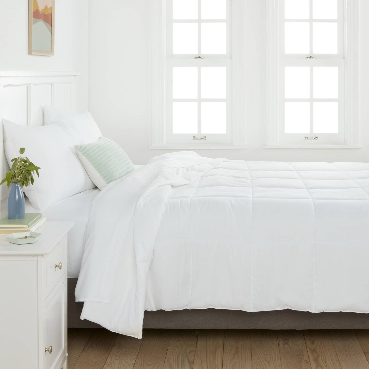 A white bedroom with an uncovered white duvet on the bed.