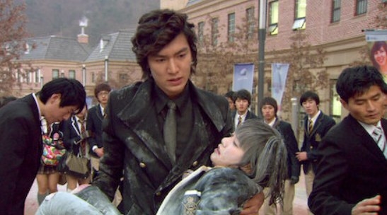 Jun-pyo carries an unconscious Jandi in his arms as a crowd looks on