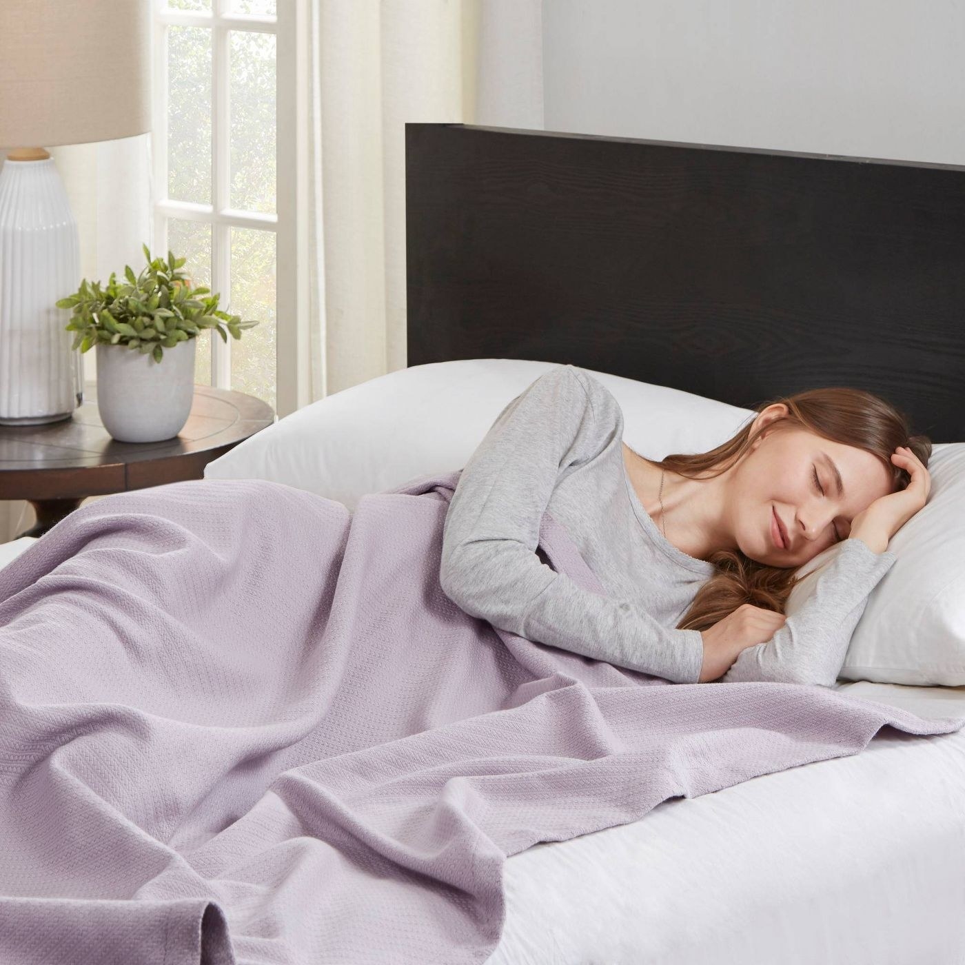 A woman sleeps comfortably in a lavender colored blanket
