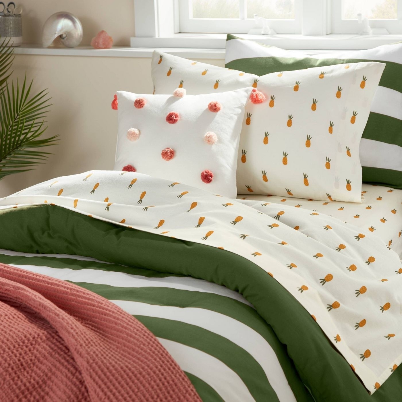 A bed with white sheets that have a pineapple design