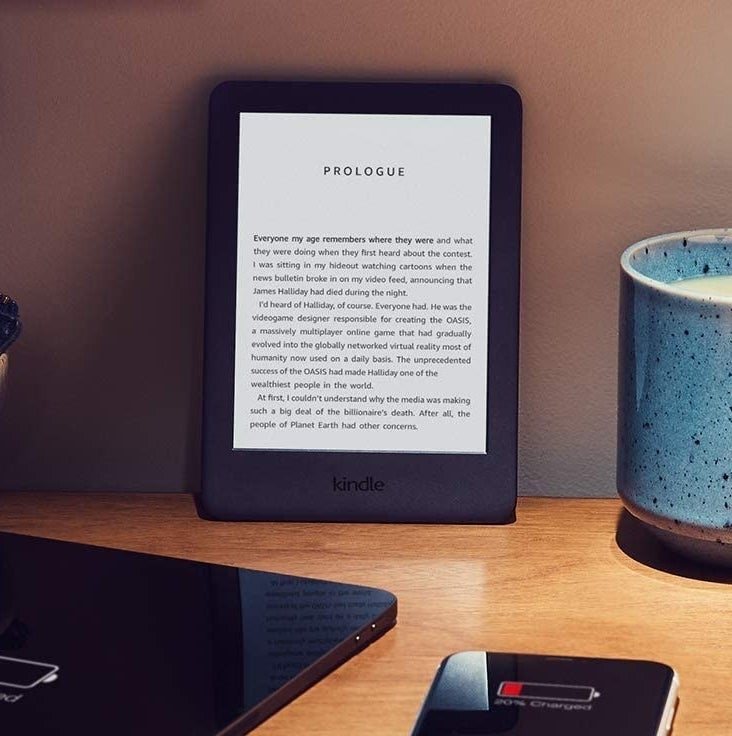 The Kindle on a desk surrounded by a mug and gadgets