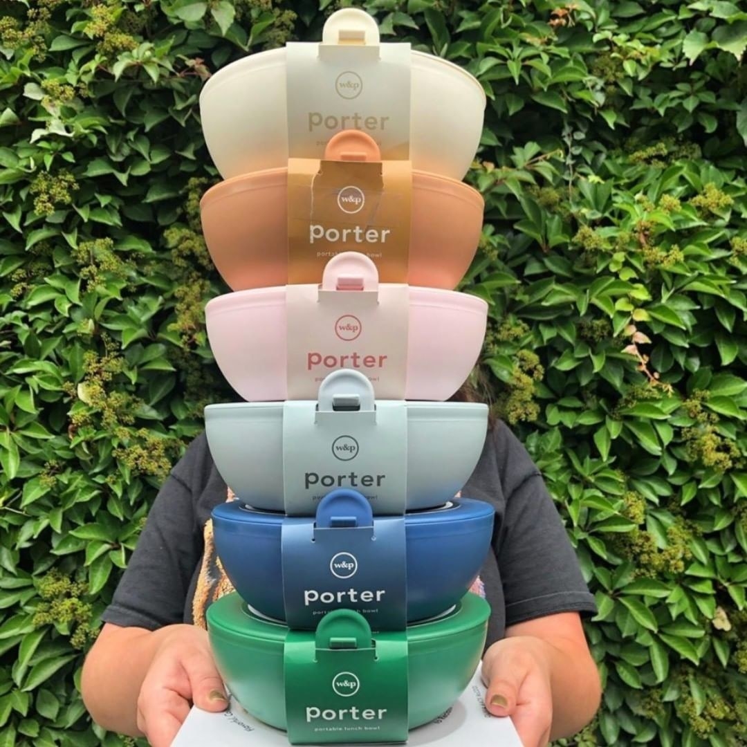 someone holding a stack of the food containers in different colours