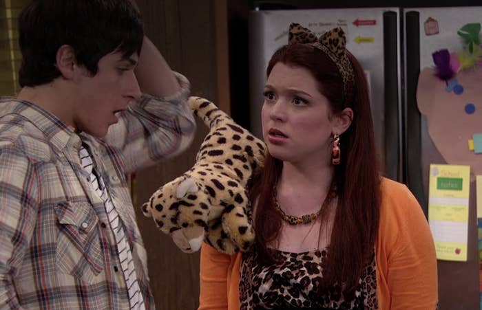 Harper looks shocked in a leopard print dress, leopard ear headband, orange cardigan, and wears a leopard stuffed animal on her shoulder