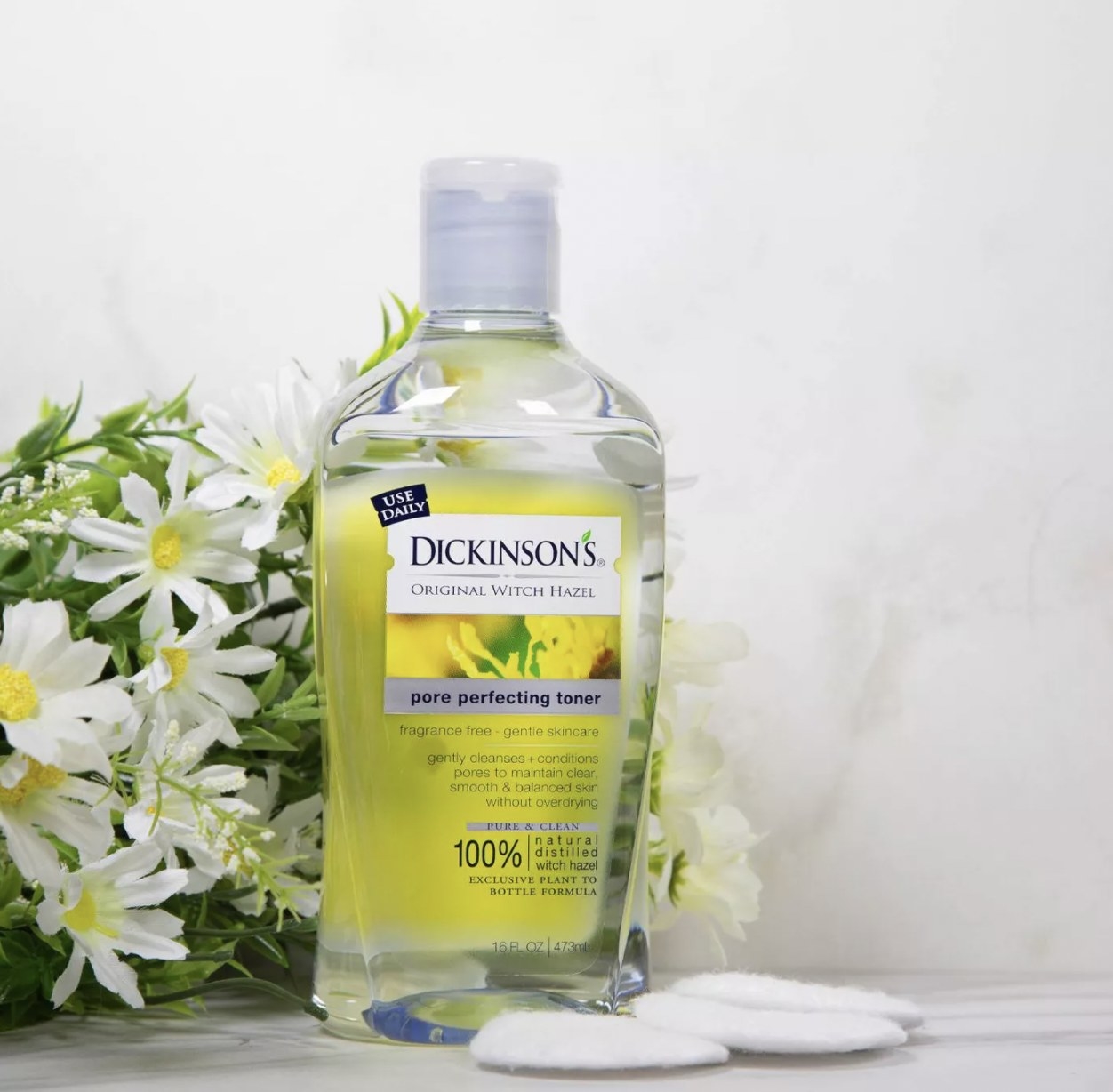 Bottle of Dickinson&#x27;s pore perfecting toner next to white flowers
