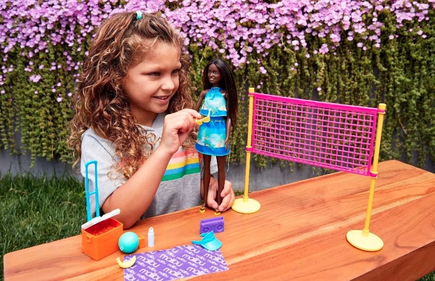 A child playing with the Barbie and volleyball accessories
