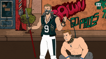 Rob Gronkowski raises a spear while holding a leashed, collared, and shirtless Nick Foles in