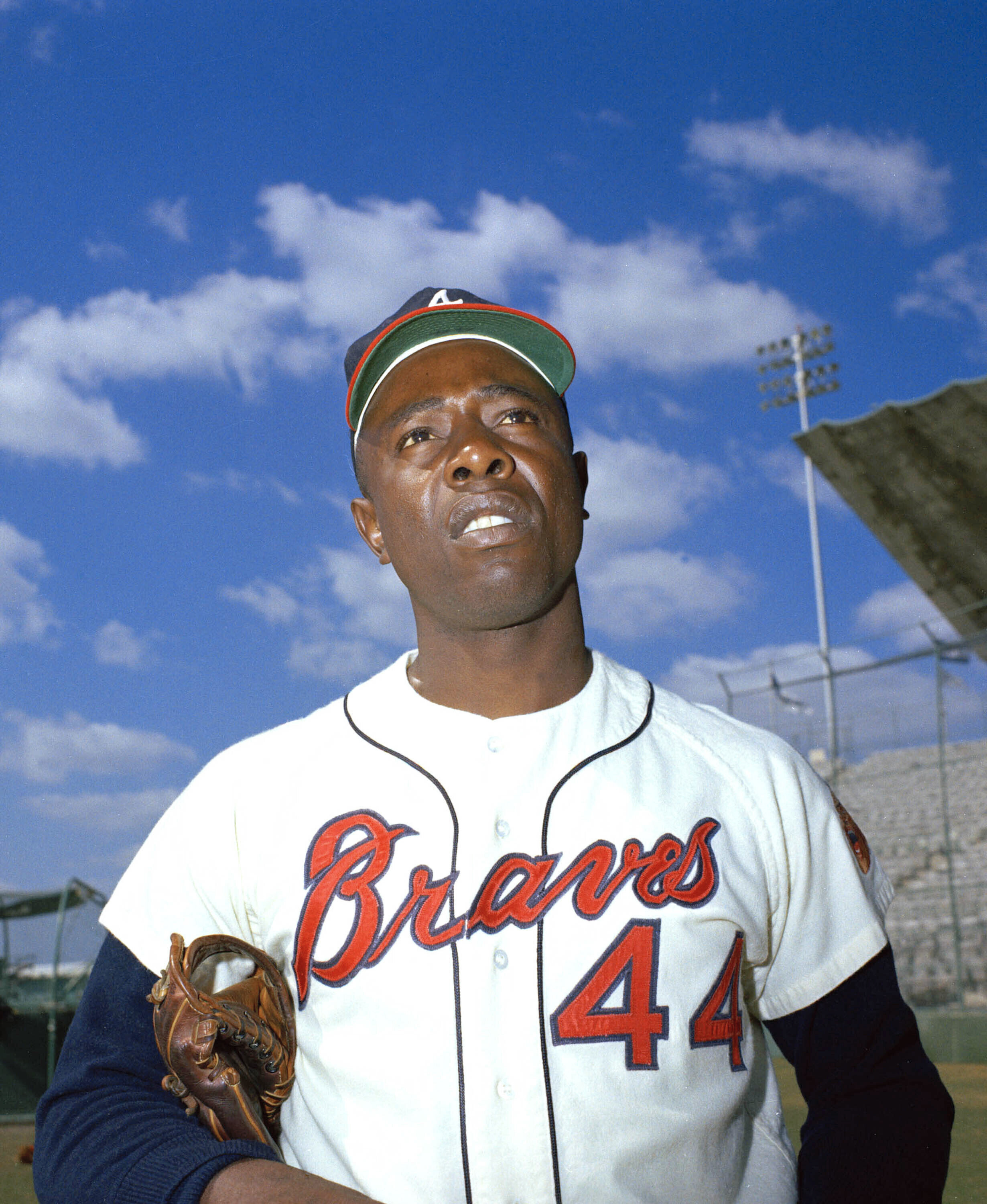 Hank Aaron in his Braves 44 jersey with a glove under one arm 