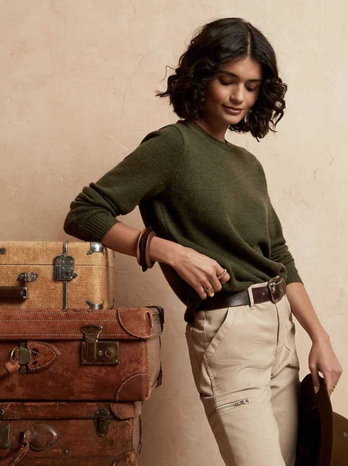 model in dark green crewneck sweater and belted high-rise pants