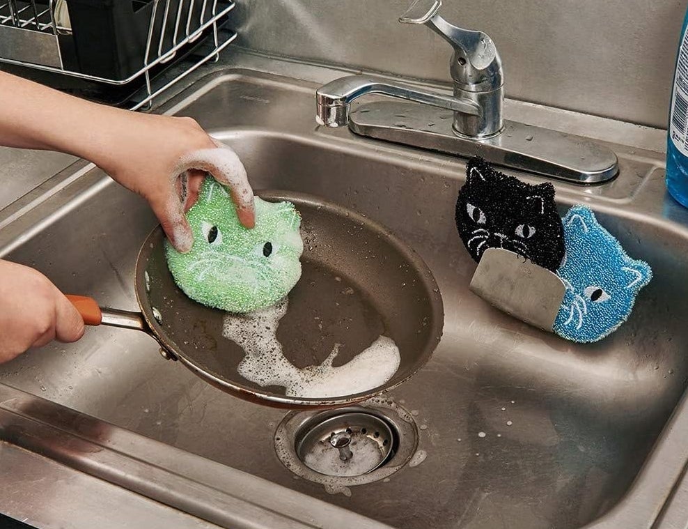 Model using cat-shaped sponge to wash pan