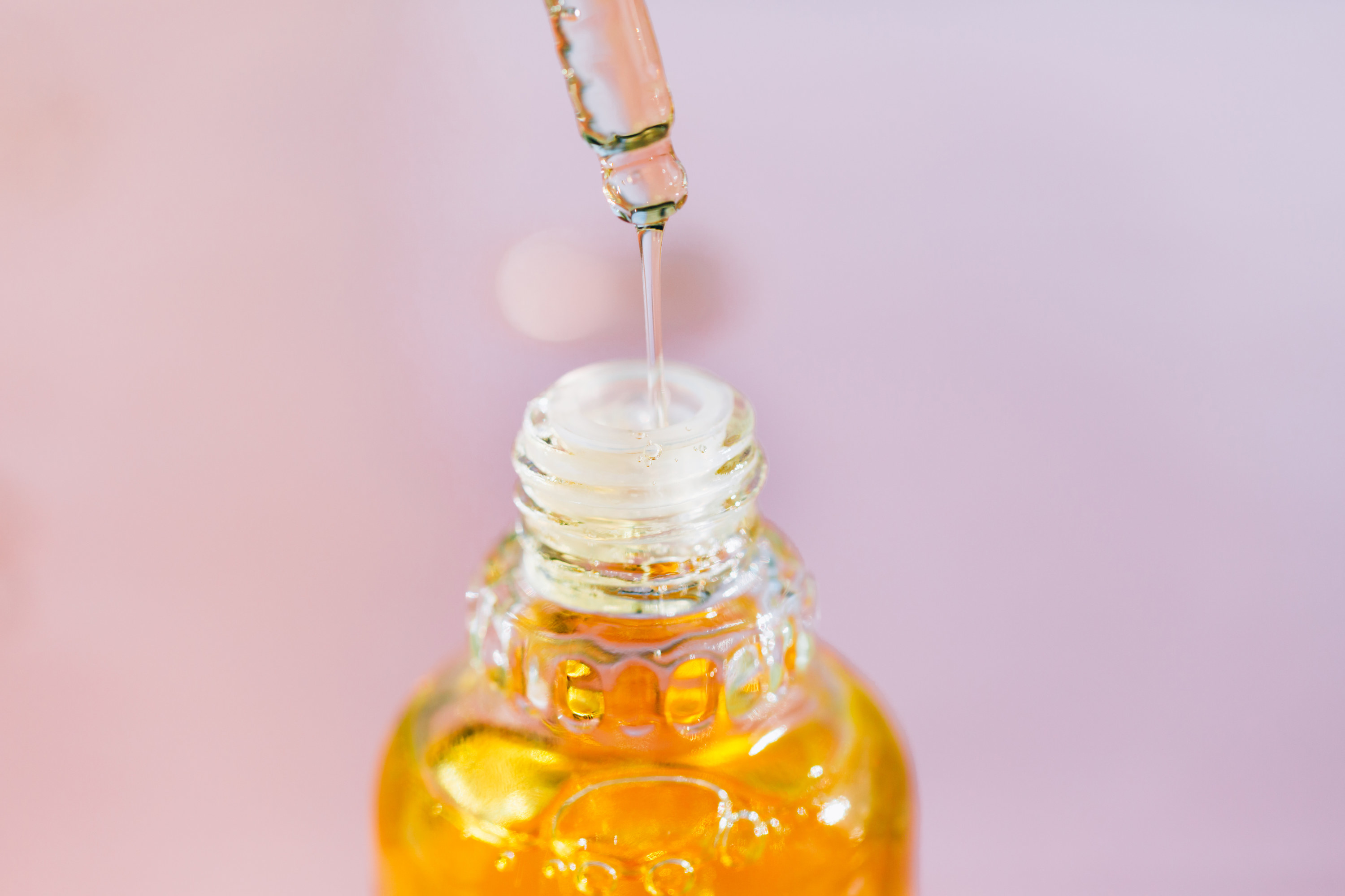 A dropper pouring oil into a bottle