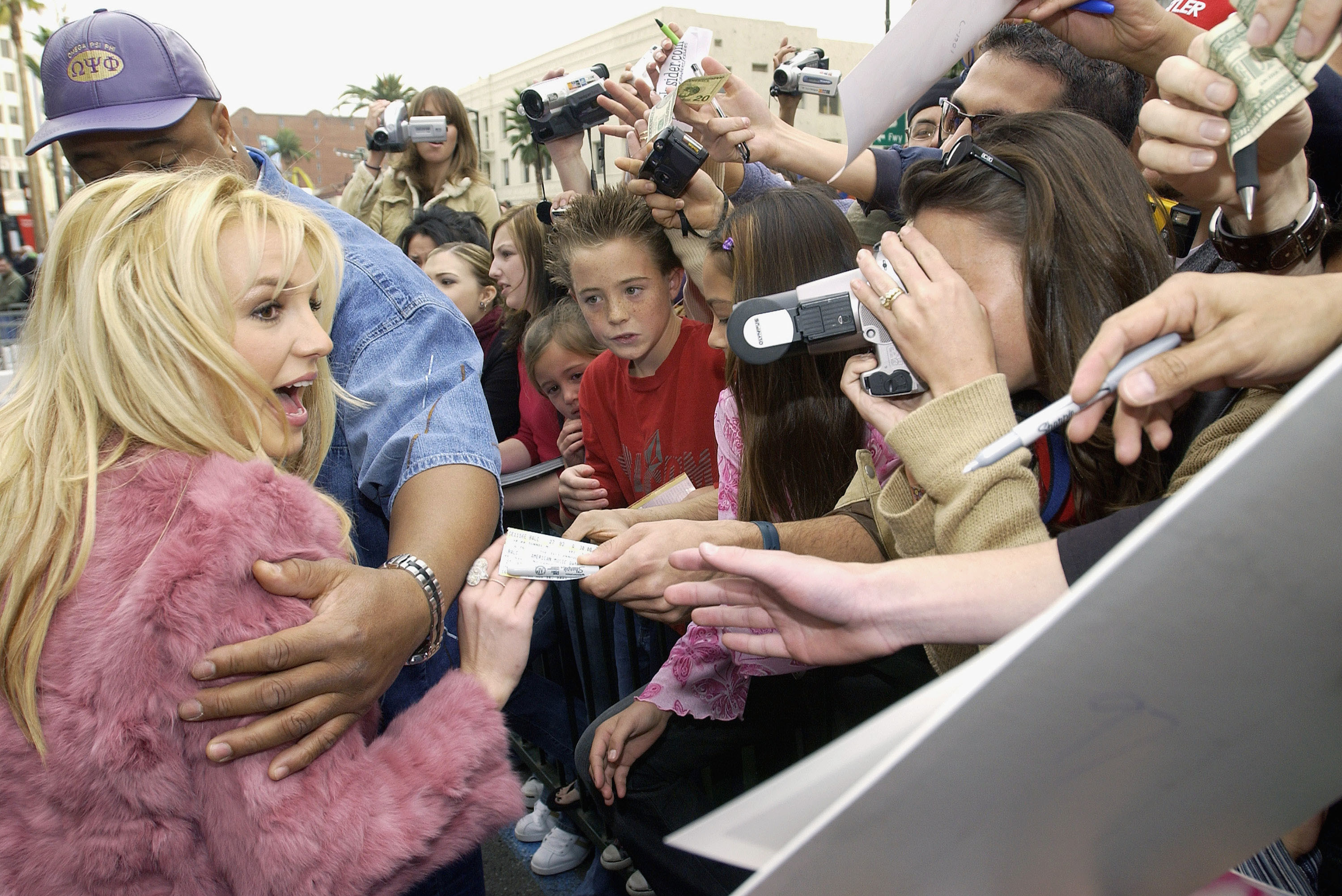 Britney spears being led away from a crowd of fans