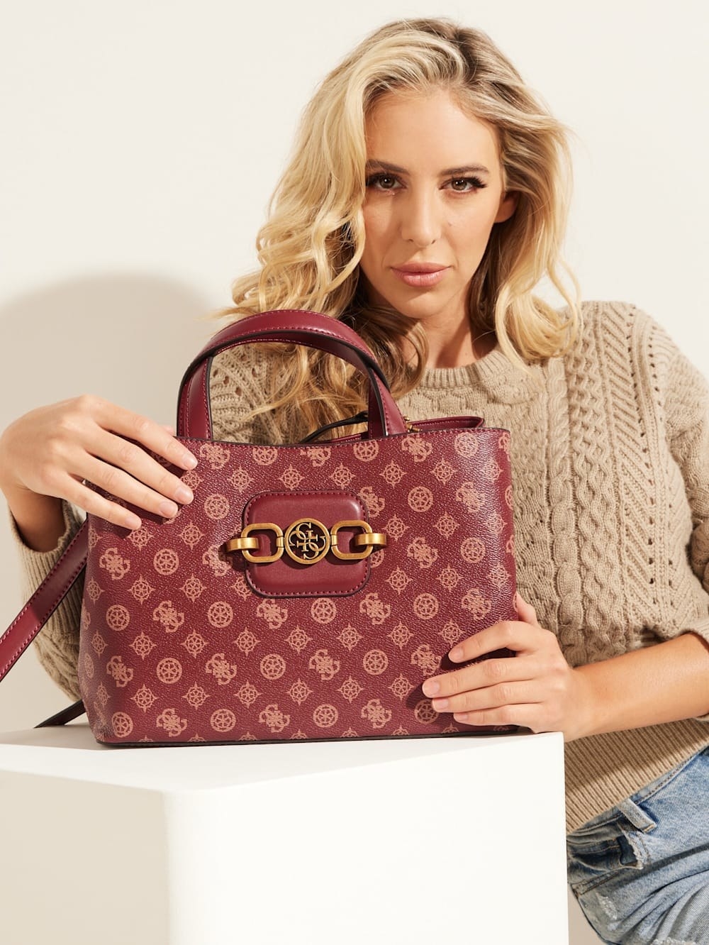 model holds red Guess logo satchel with gold buckle