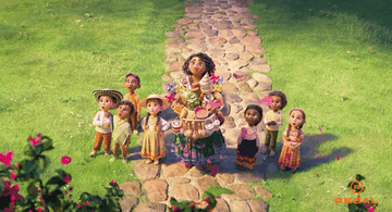 Mirabel from "Encanto" stands next to some children and they watch in awe as flowers bloom around them