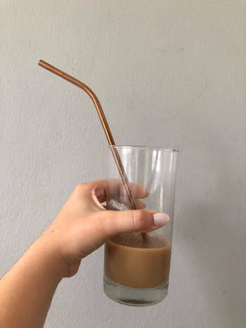 Reviewer holding glass with steel straw inside of it