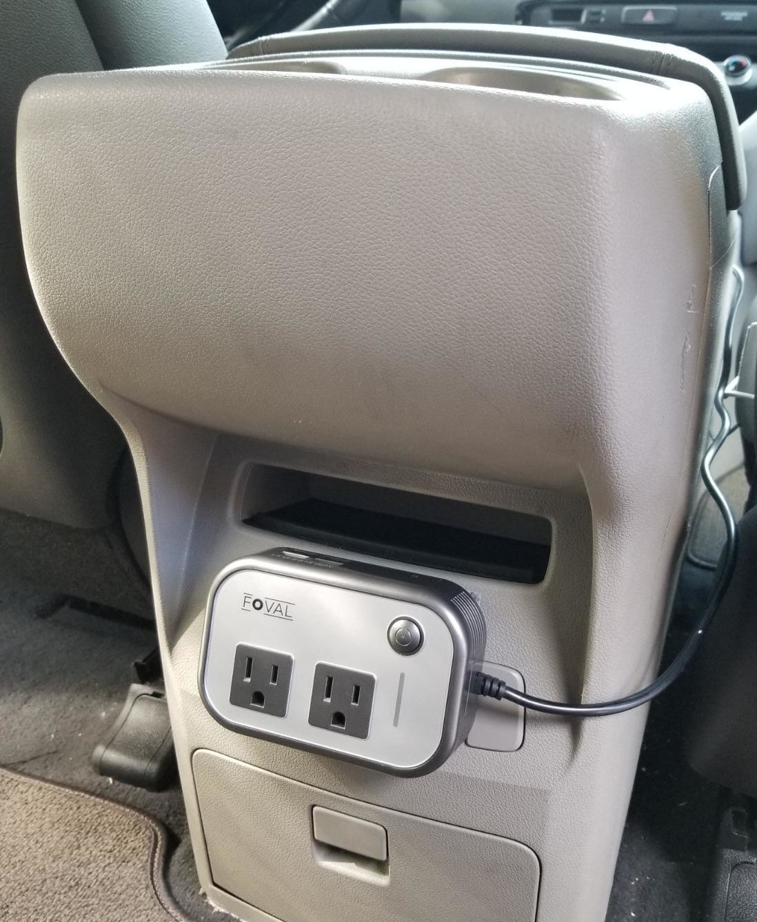 Reviewer image of white and silver AC power converter plugged into back of car