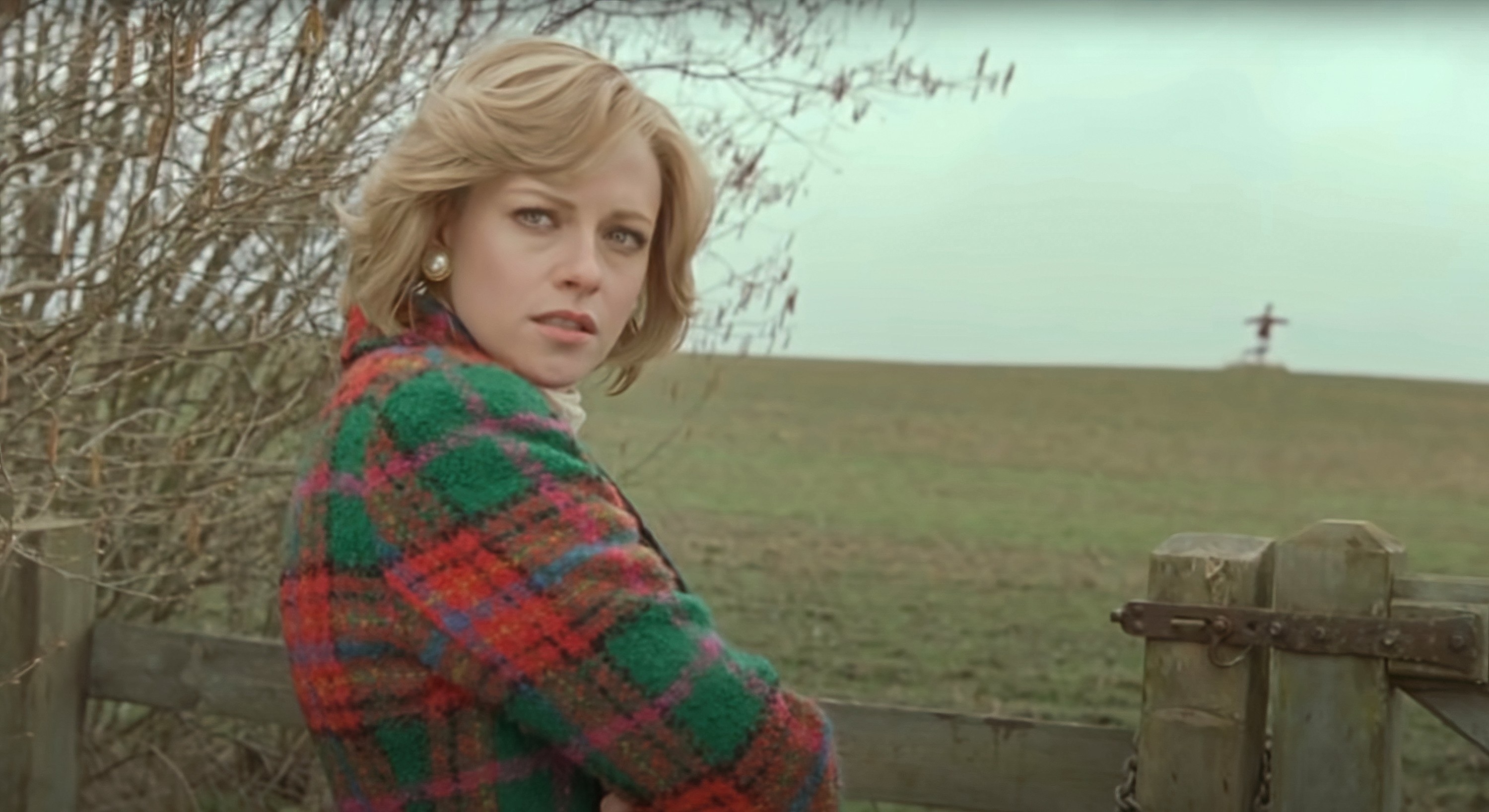Kristen Stewart stands by a field with a scarecrow in it