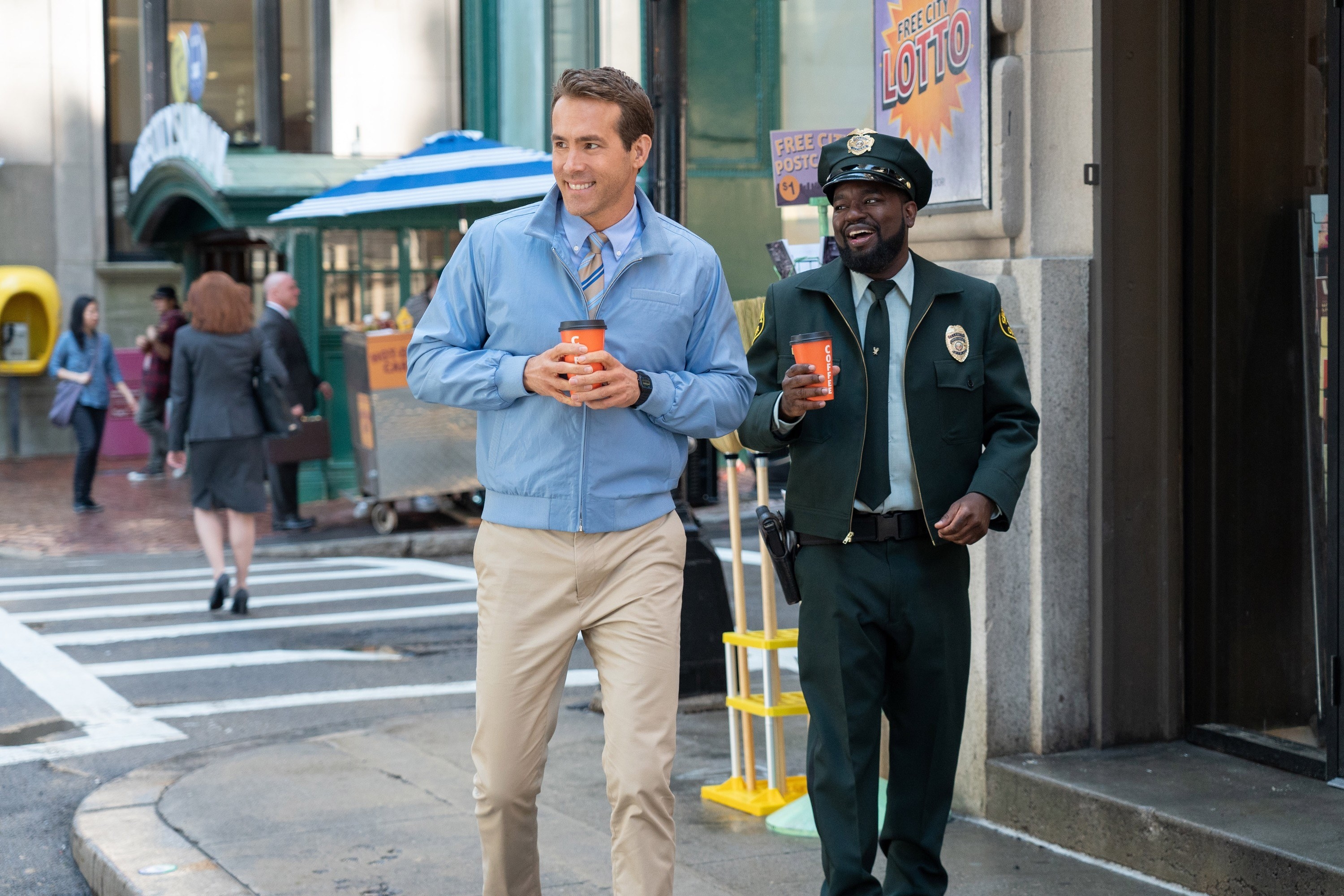 Ryan Reynolds and Lil Rel Howery walk down the street with coffees