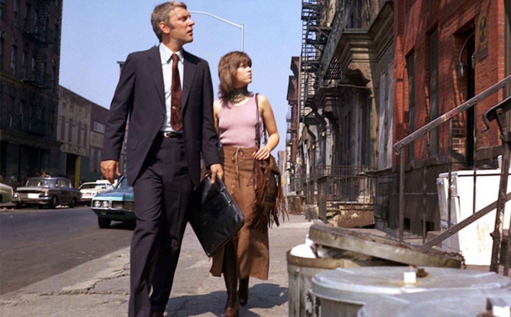 A man in a suit and woman in causal clothing walking together in the street.