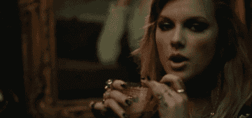 a gif of taylor swift sipping a drink in the &quot;end game&quot; music video
