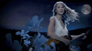 a gif of taylor swift playing guitar and singing in the &quot;fifteen&quot; music video