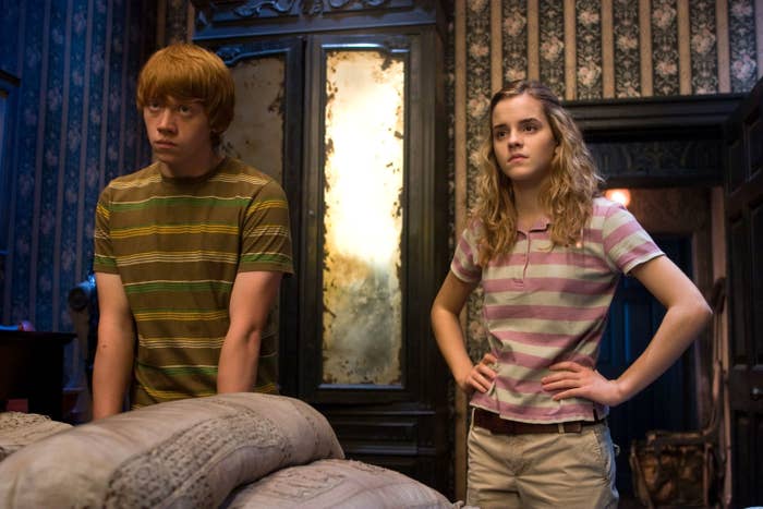 Rupert Grint stands next to Emma Watson while she has her hands on her hips