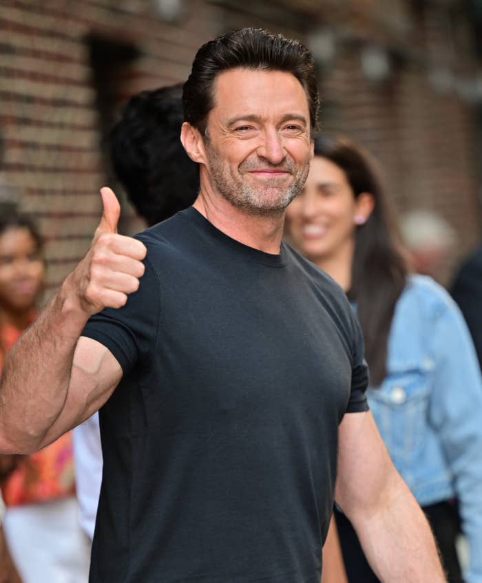 Hugh giving a thumbs to the camera as he walks out of a building
