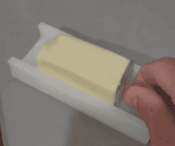 GIF of someone greasing a frying pan using butter that's attached to the butter stick