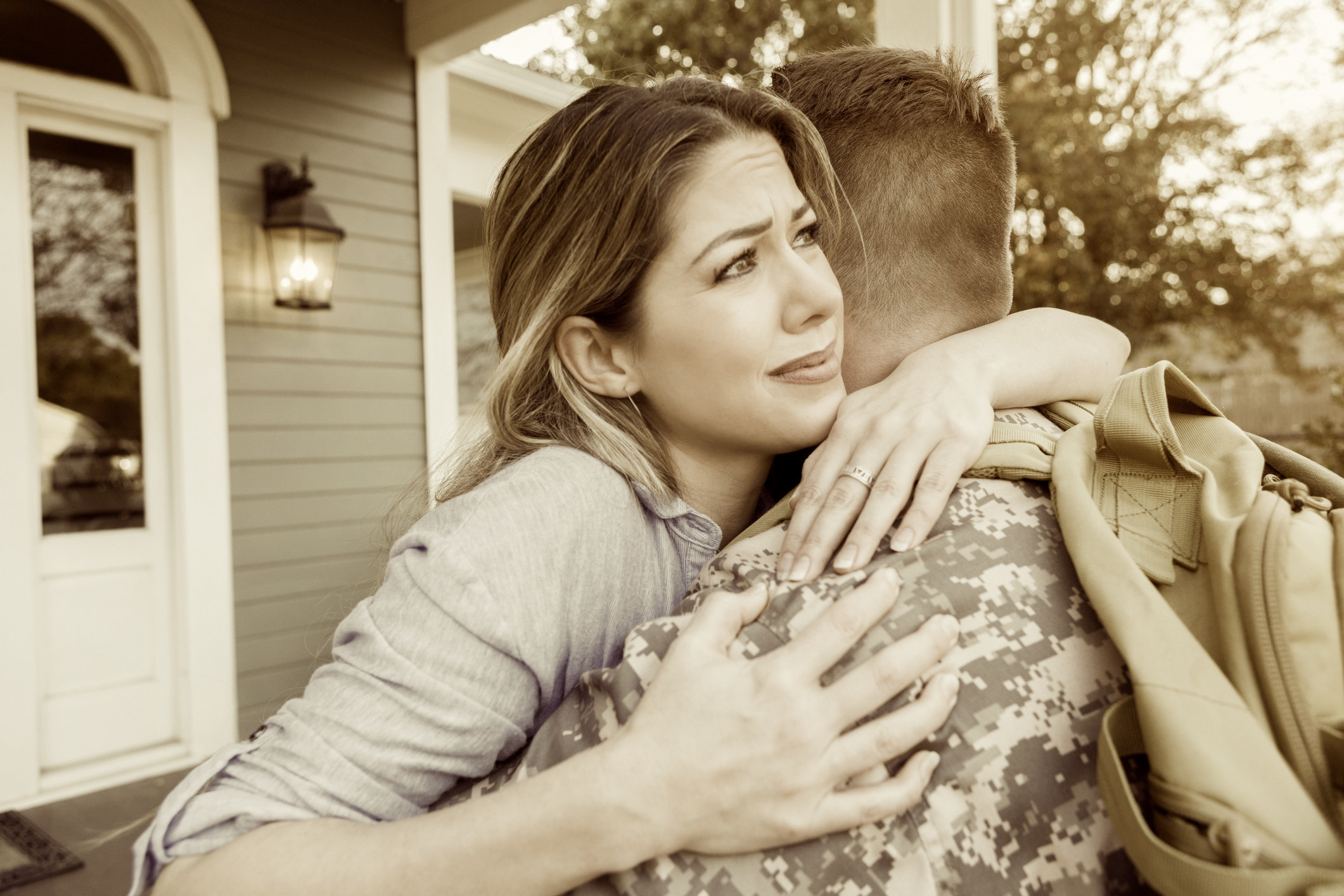 Upset mid adult woman hugs her military husband