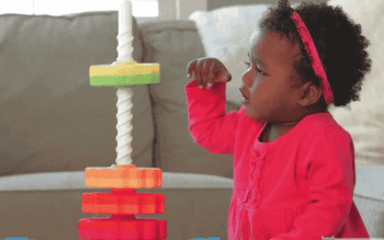 small toddler playing with spinning stackable toy
