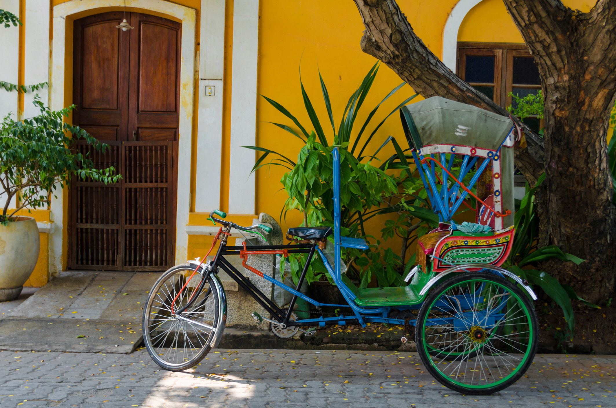 A rickshaw parked next to a colorful building.
