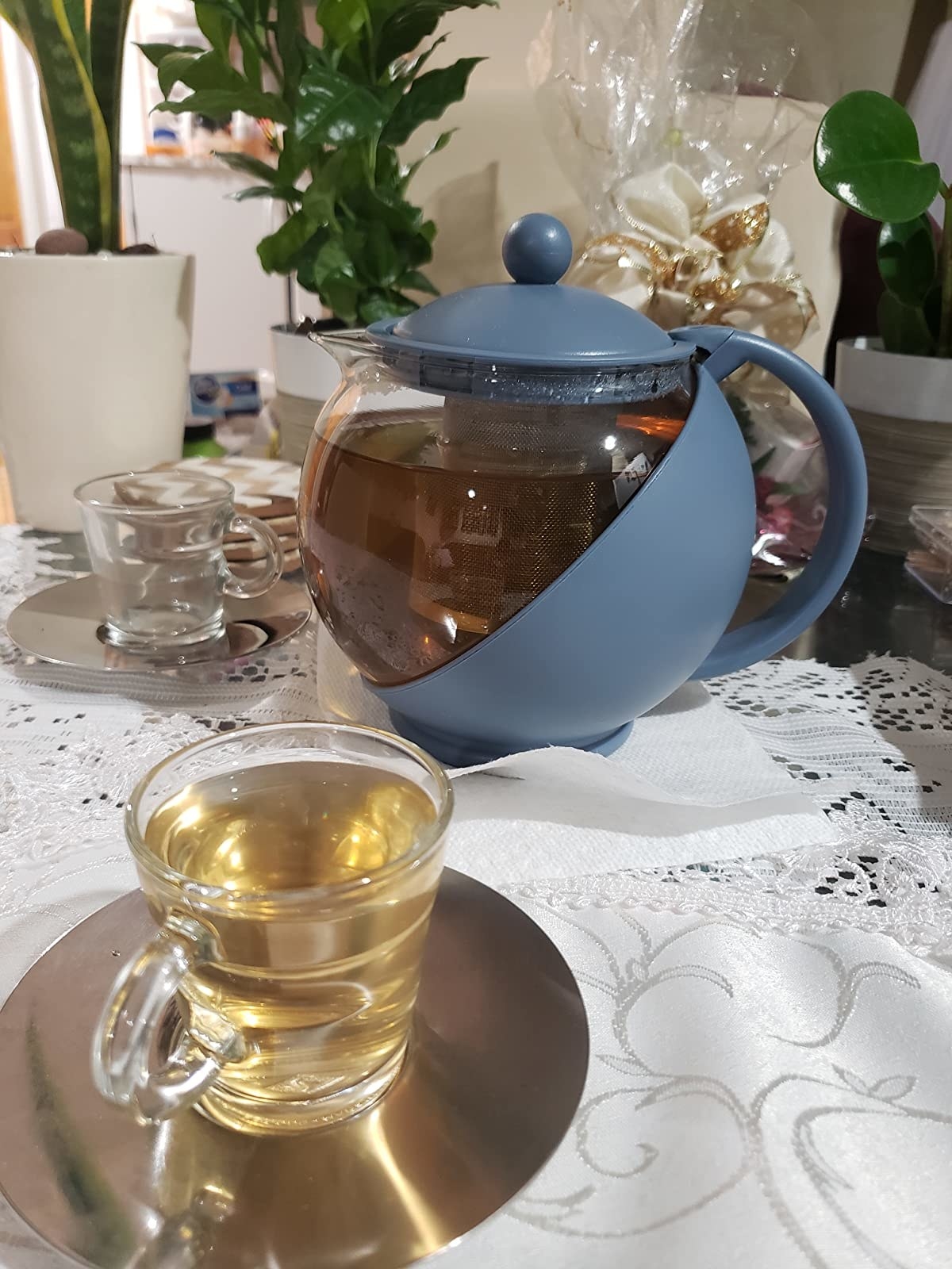 Half glass and half blue teapot next to glass teacup filled with tea